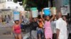 Medam pote bokit dlo nan moman gen yon rate dlo ak gaz pou kwit manje ak lot pwodwi premye nesesite apre manifestasyon popile yo te lakoz moun oblije rete lakay yo nan Potoprens, Samdi 17 Septanm, 2022. 