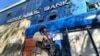 FILE - A Taliban fighter stands guard outside a bank, in Kabul, Afghanistan, Feb. 13, 2022.