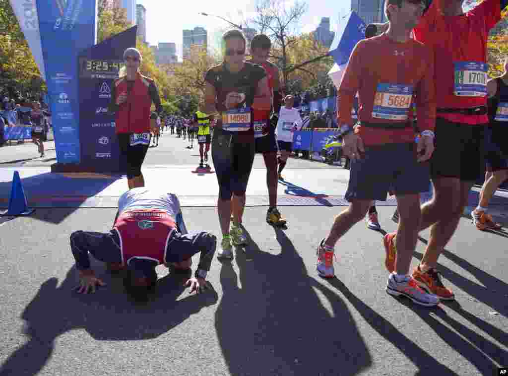 Un coureur embrasse le sol au moment où il franchit la ligne d'arrivée avec à ses cotes d’autres participants du marathon de New York à New York, le 2 novembre 2014.