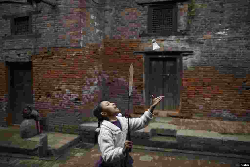 A girl plays badminton along the street outside old houses in the ancient city of Bhaktapur, near Nepal's capital Kathmandu.