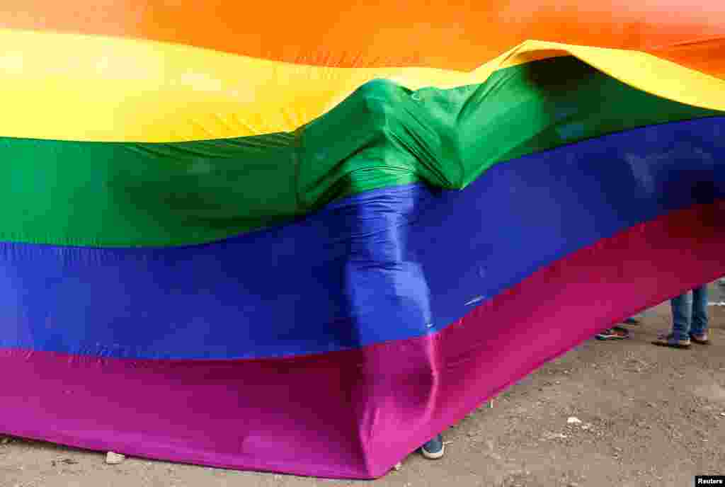 A participant stands behind a rainbow flag during a vigil in memory of the victims of the Pulse gay nightclub shooting in Orlando, Florida, in Mumbai, India.