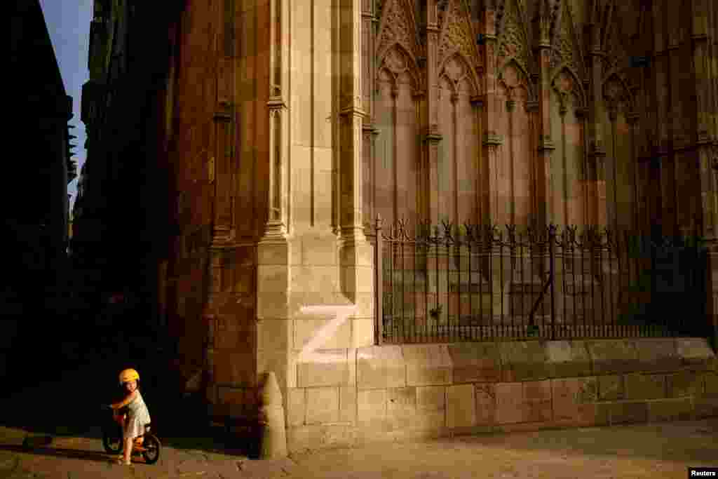 A child rides a bike next to the cathedral wall in Barcelona, painted with the letter &#39;Z&#39;, the symbol of the Russian military, in Barcelona, Spain, Sept. 17, 2022.
