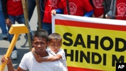 A father carries his son while holding an improvised hammer to symbolize labor during a rally near the Presidential Palace in Manila, Philippines, to pay tribute to workers in celebration of International Labor Day Wednesday, May 1, 2019. The…