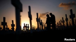 FILE - A couple grieves at a grave in a cemetery Coral Gables, Florida, Feb. 16, 2008. A new study shows that suicide rates in the U.S. jumped 24 percent between 1999 and 2014.