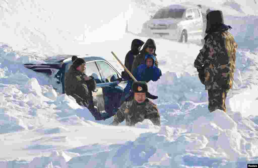 Police digging out a car trapped in a snow slide in Altay, Xinjiang Uighur Autonomous Region, China, Jan. 3, 2016.