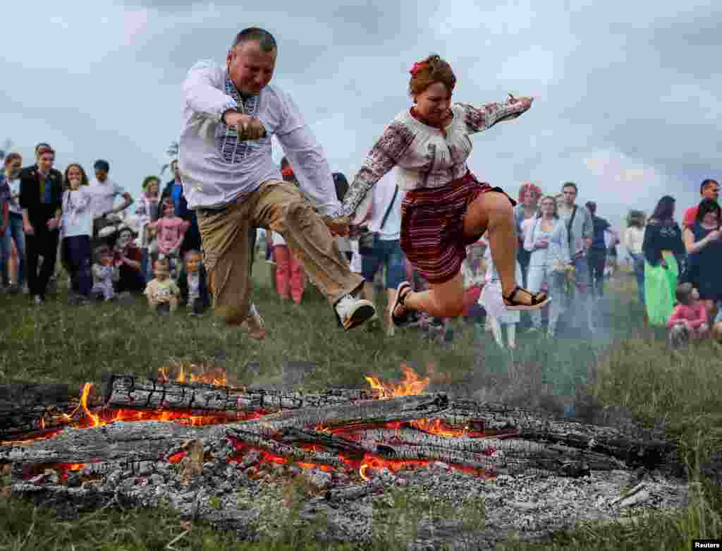 People jump over a campfire during a traditional Ivana Kupala (Ivan the Bather) holiday celebration in Kyiv, Ukraine, July 6, 2016. The ancient tradition - originating from pagan times - is usually marked with grand overnight festivities during which people sing and dance around campfires, believing it will purge them of their sins and make them healthier.