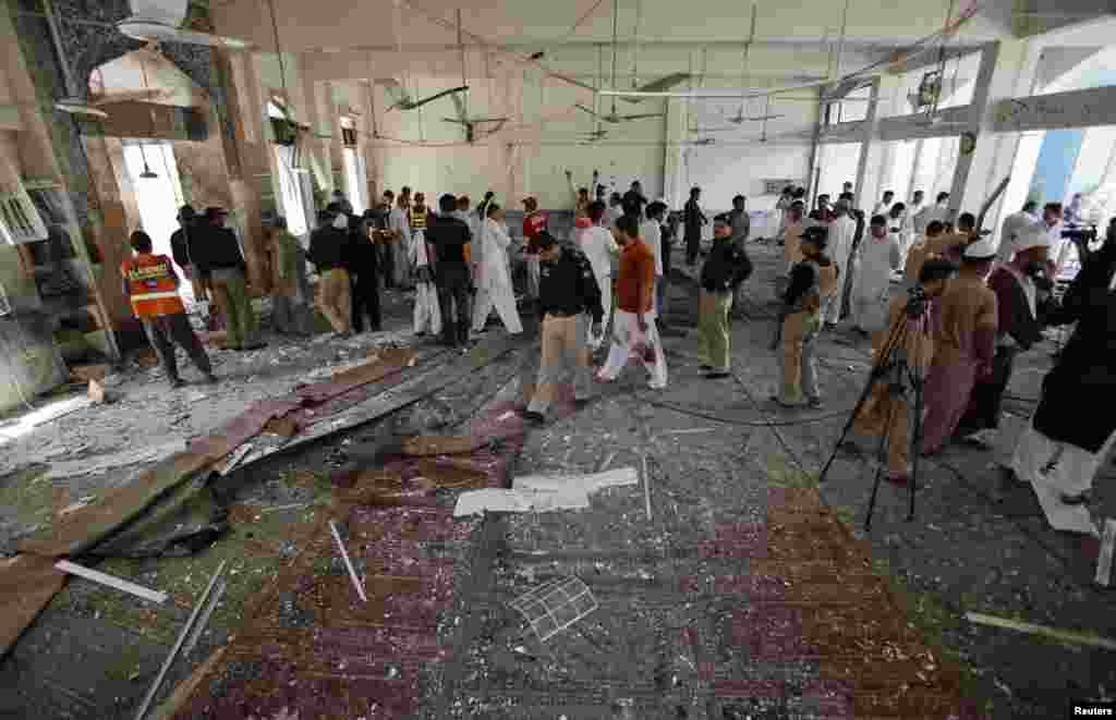 Security officials, rescue workers and members of the media gather at the site of a suicide bomb attack in a Shi'ite Muslim mosque in Peshawar, Pakistan, June 21, 2013.