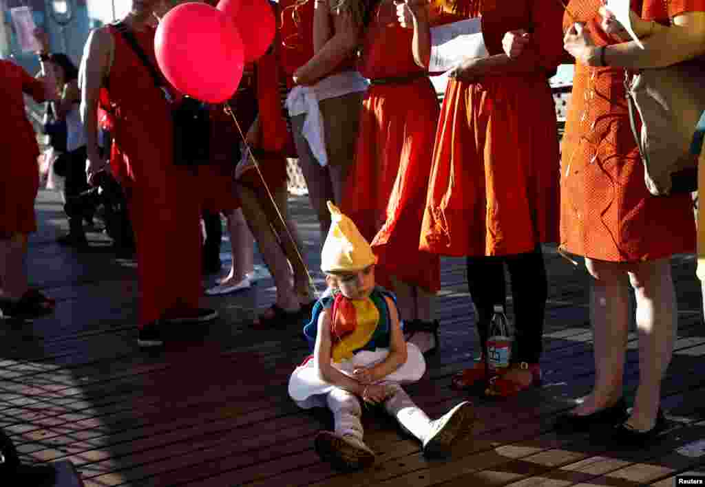 Four-year-old Izzy Rogers sits down amid people holding balloons on the Brooklyn Bridge in New York, U.S., June 14, 2016, as they line up to form a "human rainbow" during a gathering to remember the victims of the mass shooting in Orlando.