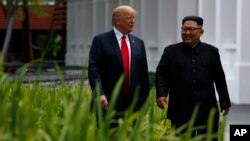 Predsjednik Donald Trump korača sa sjevernokorejskim liderom Kim Jong Unom na ostrvu Santosa, 12. juna 2018, u Singapuru.