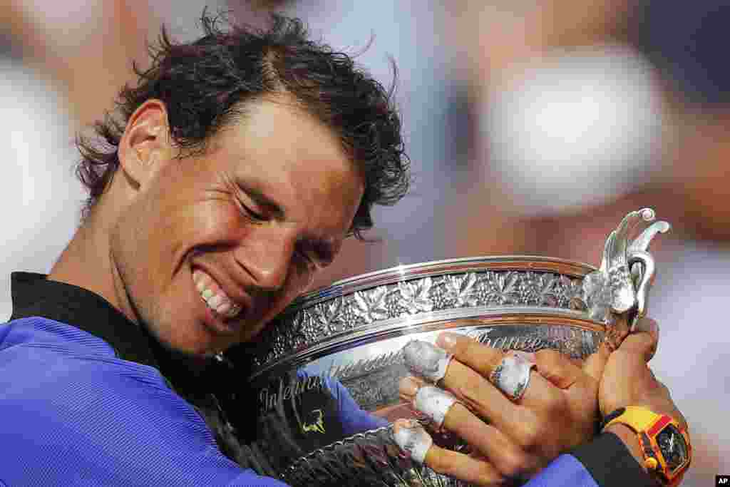 Spain's Rafael Nadal holds the trophy as he celebrates winning his tenth French Open title against Switzerland's Stan Wawrinka in three sets, 6-2, 6-3, 6-1, during their men's final match of the French Open tennis tournament at the Roland Garros stadium, in Paris, France.