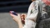 FILE - In this April 8, 2019, photo, a woman browses her smartphone. For many journalists working in Myanmar, the smartphone is a lifeline.