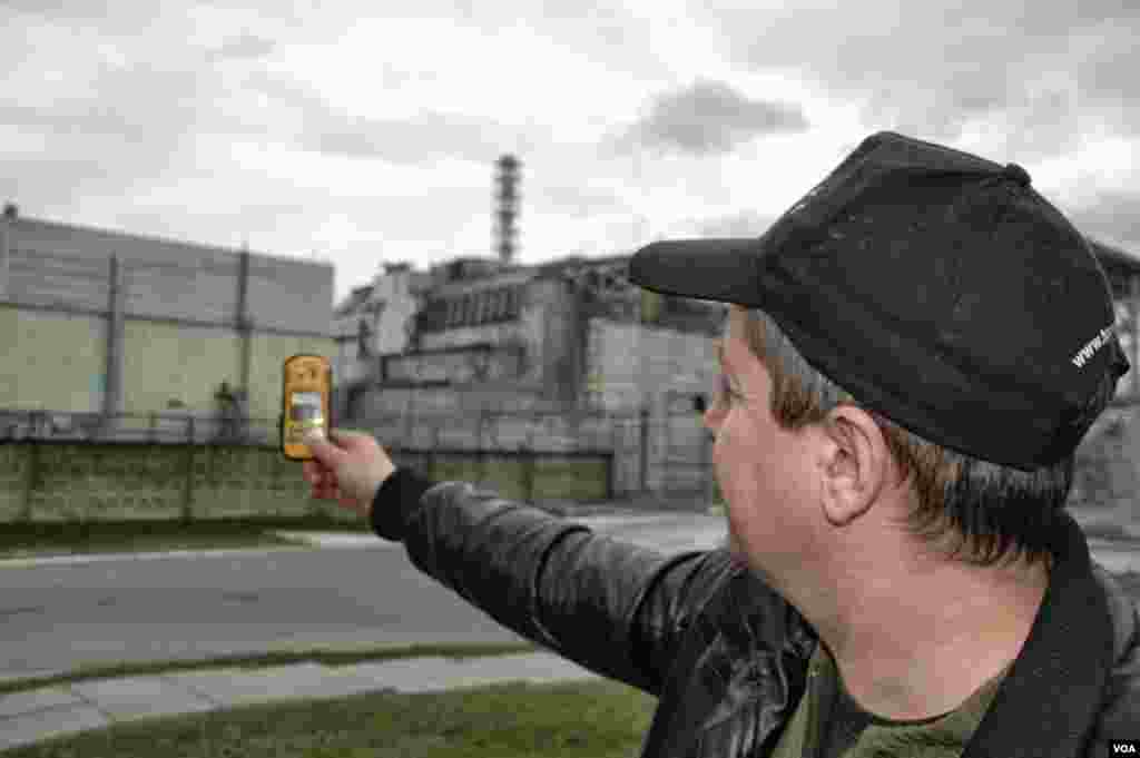 Driver Igor Bordnarch, a frequent visitor to the Chernobyl reactor site, checks radiation readings just 240 meters from the destroyed reactor, Chernobyl Nuclear Power Plant, Ukraine, March 19, 2014. (Steve Herman/VOA)