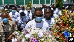 Pierre Gary Bernadotte, anggota partai politik PHTK presiden yang terbunuh, membawa bunga ke sebuah tempat di luar istana presiden untuk mengenang mendiang Presiden Jovenel Moise di Port-au-Prince, Haiti, Rabu, 14 Juli 2021. (Foto: AP)
