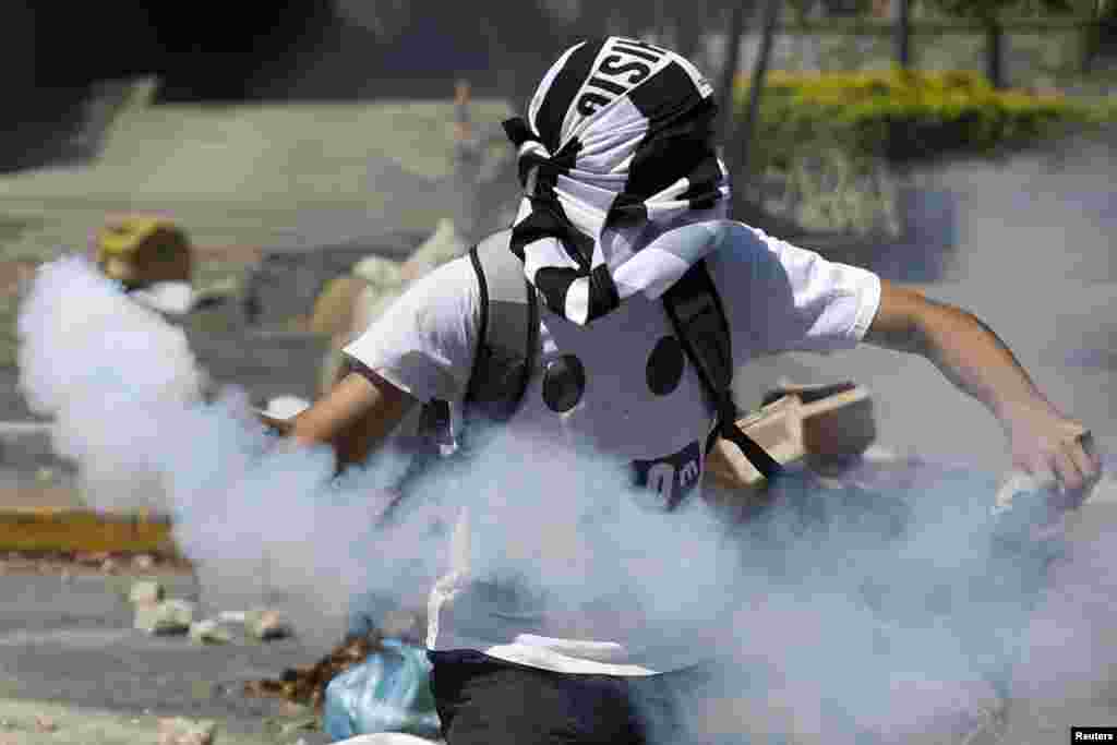 An anti-government protester throws a gas canister back at police during riots in Caracas, April 6, 2014. Protesters have been on the streets since early February calling for President Nicolas Maduro's resignation and complaining about a litany of problems from rampant crime to food shortages.