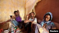 FILE - Illegal immigrants from Ethiopia attempting to cross into Yemen smoke shisha in their makeshift shelter in Bosasso, northern Somalia's breakaway Puntland region, Apr. 14, 2015. 