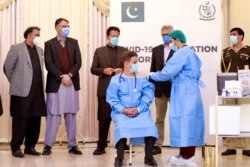 Pakistan's Prime Minister Imran Khan, center back, watches as the first Chinese-made COVID-19 vaccine is administered to a front-line health worker in Islamabad, Feb. 2, 2021, in this photograph taken by Pakistan's Press Information Department.