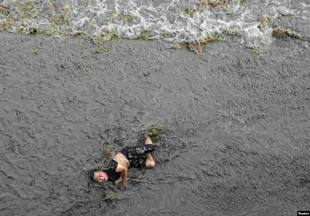 A man falls off a bridge while tidal waves approaching him, on the banks of Qiantang River in Hangzhou, Zhejiang province, China, July 25, 2016.