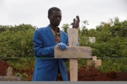 FILE - A Congolese man holds a cross during the burial service of a Congolese woman who died of Ebola, at a cemetery in Butembo.