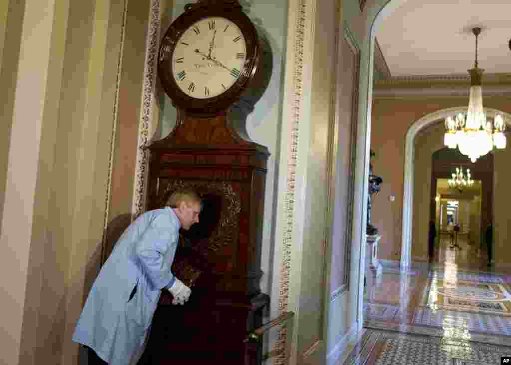 Richard Doerner, spesialis museum pada Komisi Senat AS untuk Seni, mengecek Jam Ohio saat ia mengoperasikan kembali jam di luar Ruang Senat di Gedung Kongres itu (17/10). Jam tersebut berhenti selama 16 hari karena para pekerja yang mengurusnya dirumahkan sementara. (AP/ Evan Vucci)