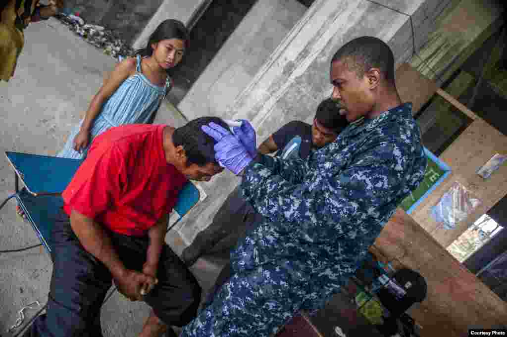 A U.S. hospital corpsman assists Philippine nurses in treating a patient's head wound at the Immaculate Conception School refugee camp, Guiuan, Philippines, Nov. 17, 2013. (U.S. Navy)