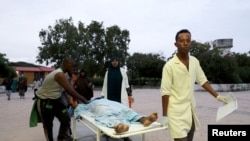 Paramedics and civilians carry an injured person on a stretcher at Madina hospital after a blast at the Elite Hotel in Lido beach in Mogadishu, Somalia, Aug. 16, 2020. 