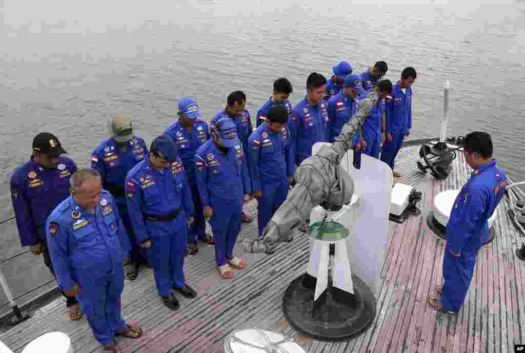Members of Indonesia's Marine Police pray on board a search and rescue ship before a search operation for the missing AirAsia flight 8501, at Pangkal Pinang port in Sumatra Island, Indonesia, Dec. 29, 2014.