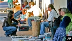 In this file photo, sellers and buyers trade under the historic portal in Old Town Albuquerque, N.M., Feb. 8, 2006. Native American artists and craftsmen say counterfeit "tribal" art manufactured abroad devalues the market and robs them of business.