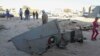 People stand next to the wreckage of a government MiG Libyan fighter jet that crashed during fighting Islamist fighters, in Benghazi, July 29, 2014.