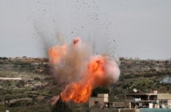 An explosion is seen following Russian airstrikes on the village of al-Bara in the southern part of Syria's northwestern Idlib province.