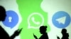 FILE - Silhouettes of mobile users are seen next to logos of social media apps Signal, Whatsapp and Telegram projected on a screen in this picture illustration.