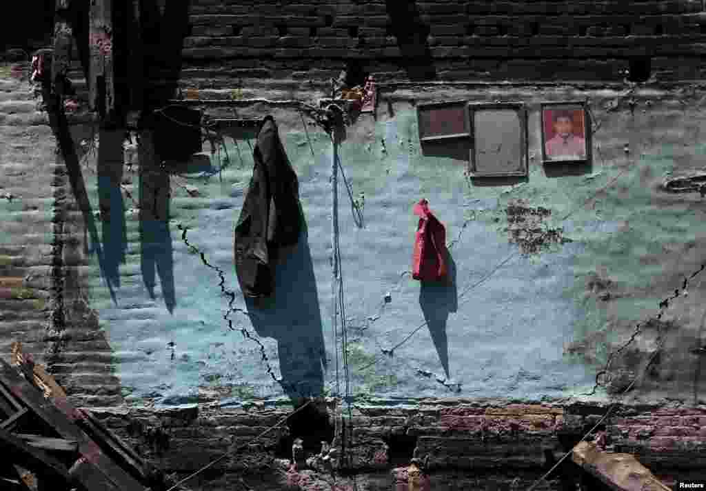 Jaket dan foto berpigura terlihat menggantung di dinding yang retak dari sebuah rumah yang rusak akibat gempa di Bhaktapur, Nepal (27/4). (Reuters/Adnan Abidi)