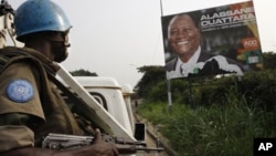 United Nations troops from Niger drive past a billboard of Ivory Coast's internationally recognized elected leader Alassane Ouattara during a patrol in Abidjan, Ivory Coast, Tuesday, Jan. 4, 2011.