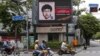People ride their motorcycles past a digital billboard showing a sketch of the main suspect in Monday's attack on Erawan shrine, in Bangkok, Thailand, August 23, 2015.