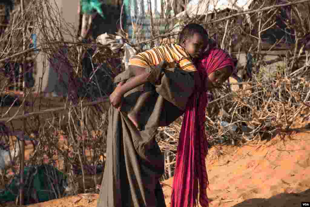 Seorang anak perempuan menggendong bayi laki-laki di kamp di Kismayo, Somalia, yang merupakan tempat penampungan pengungsi Somalia dan pengungsi yang kembali dari negara lain (27/9). (VOA/J. Patinkin)