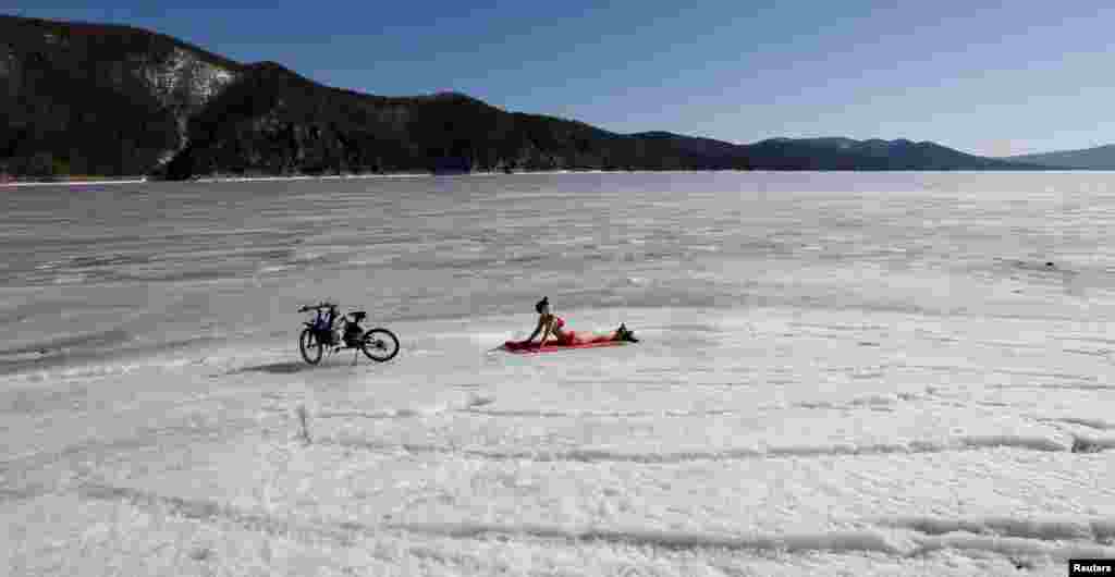 A woman enjoys the sun on the bank of the Yenisei River, with the air temperature at about 13º C (55.4º F), in the Taiga district outside Russia's Siberian city of Krasnoyarsk, April 6, 2015.