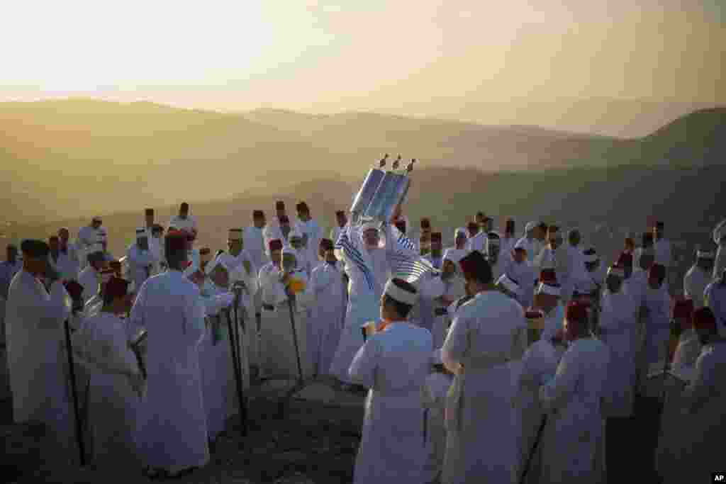 A member of the ancient Samaritan community holds up a Tora scroll as worshippers pray during the Passover pilgrimage at the religion&#39;s holiest site on the top Mt. Gerizim, near the West Bank town of Nablus.