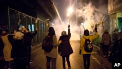 In this photograph taken Saturday, Jan. 11, 2020, protesters hold flowers as tear gas fired by police rises at a demonstration in front of Amir Kabir University in Tehran, Iran, to remember victims of a Ukrainian airplane shot down by an Iranian missile. 