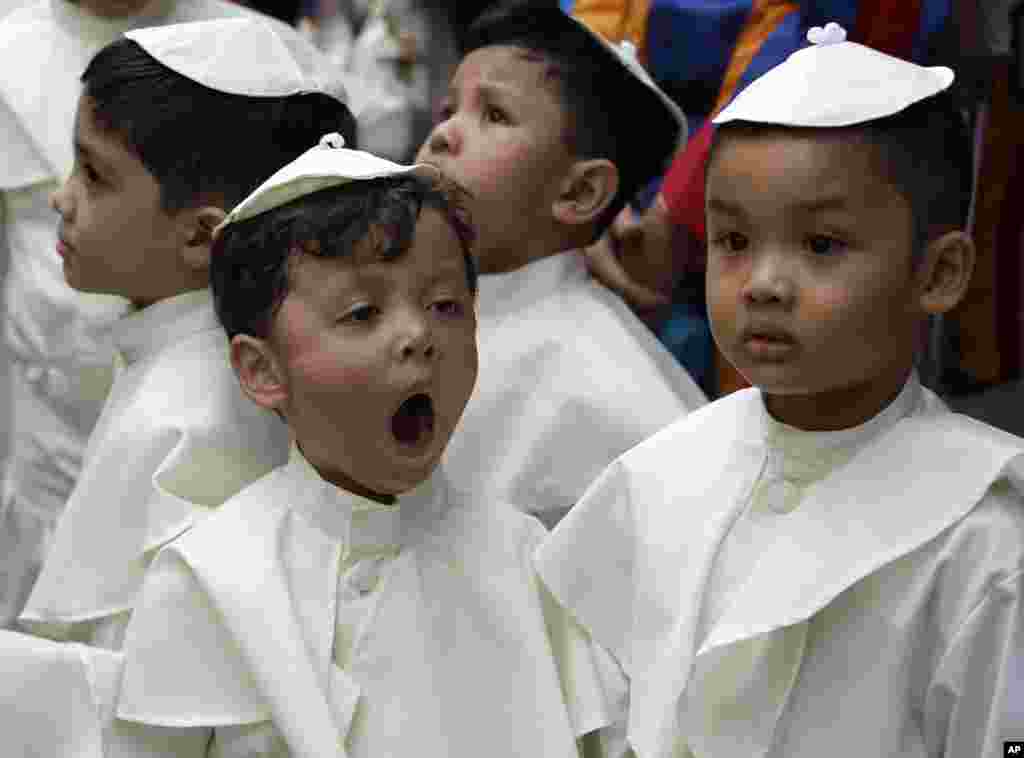 A boy dressed as a Pope yawns as he prepares to join a parade in celebration of the canonization or the elevation to sainthood in the Vatican of Roman Catholic Pope John Paul II and Pope John XXIII at suburban Quezon city, northeast of Manila, Philippine, April 27, 2014.