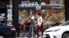 FILE - A couple walks past a Persian pizza restaurant near Persian Square in Westwood, Los Angeles.