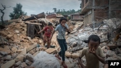 Anak-anak Nepal menutup hidung mereka saat berjalan melalui puing-puing yang menutupi sebuah jenazah di tepi kota Chautara, sekitar 80 kilometer dari Kathmandu (30/4).