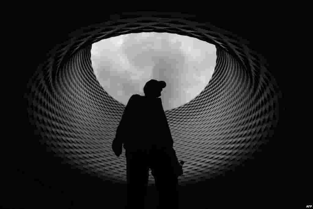 A visitor walks beneath the roof of the exhibition hall designed by Swiss architecture firm Herzog & de Meuron during the preview day of Art Basel.