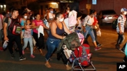 Migrants walk along a highway in hopes of reaching the distant United States, in San Pedro Sula, Honduras, Sept. 30, 2020. 