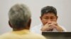 An investigator of Thailand's Department of Special Investigation interrogates a key suspect in a human trafficking ring, Samruay Chatkrod, left, in Bangkok, Thailand, Wednesday, July 1, 2015.