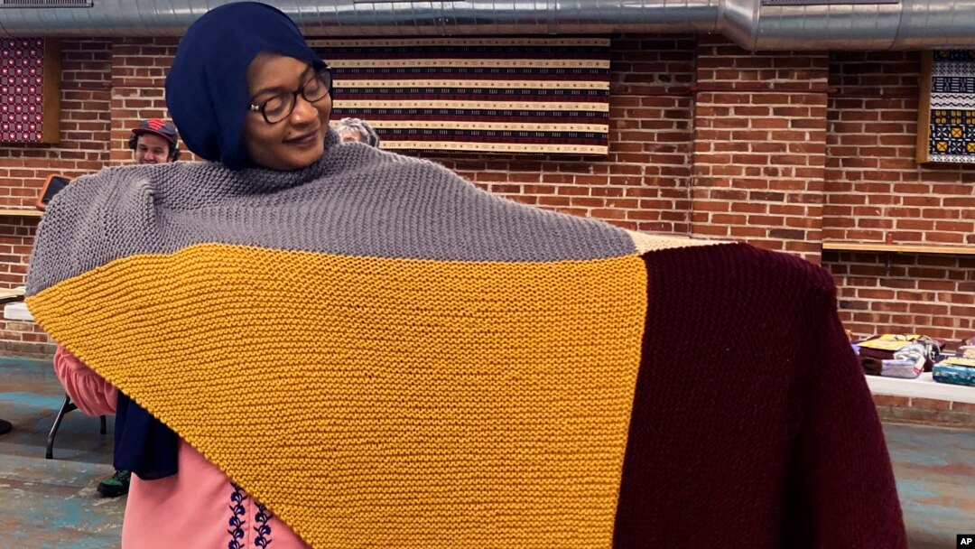 Aisha Bitini holds a handmade blanket she selected at a Welcome Blanket giveaway at the Association of Africans Living in Vermont on March 21, 2023, in Burlington, Vt. The blankets were to welcome refugees to the community. (AP Photo/Lisa Rathke)
