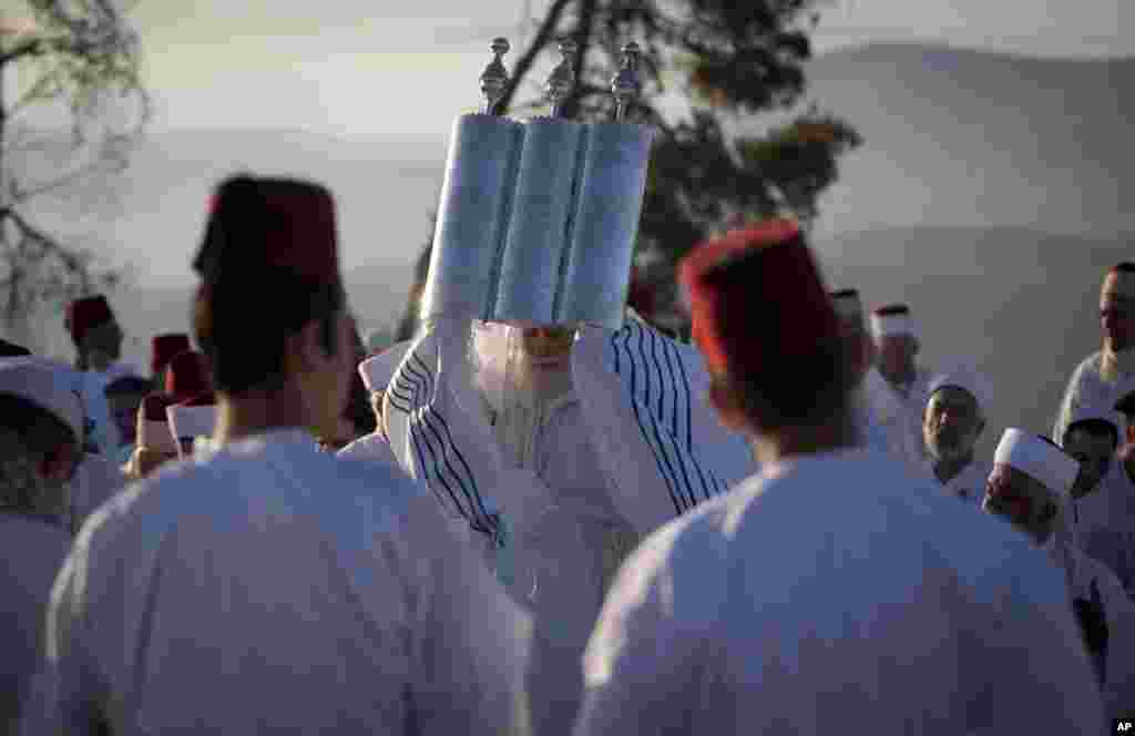 Members of the ancient Samaritan community hold up a Torah scroll during the holiday of Shavuot on Mount Gerizim near the West Bank town of Nablus.