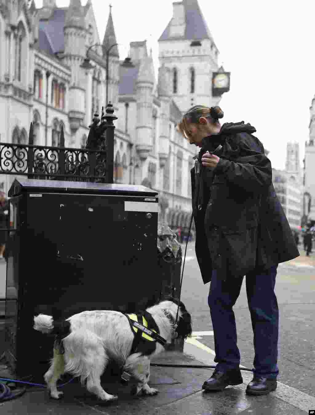A British police officer performs security checks with a sniffer dog ahead of the ceremonial funeral procession for former British Prime Minister Margaret Thatcher in London, April 17, 2013.