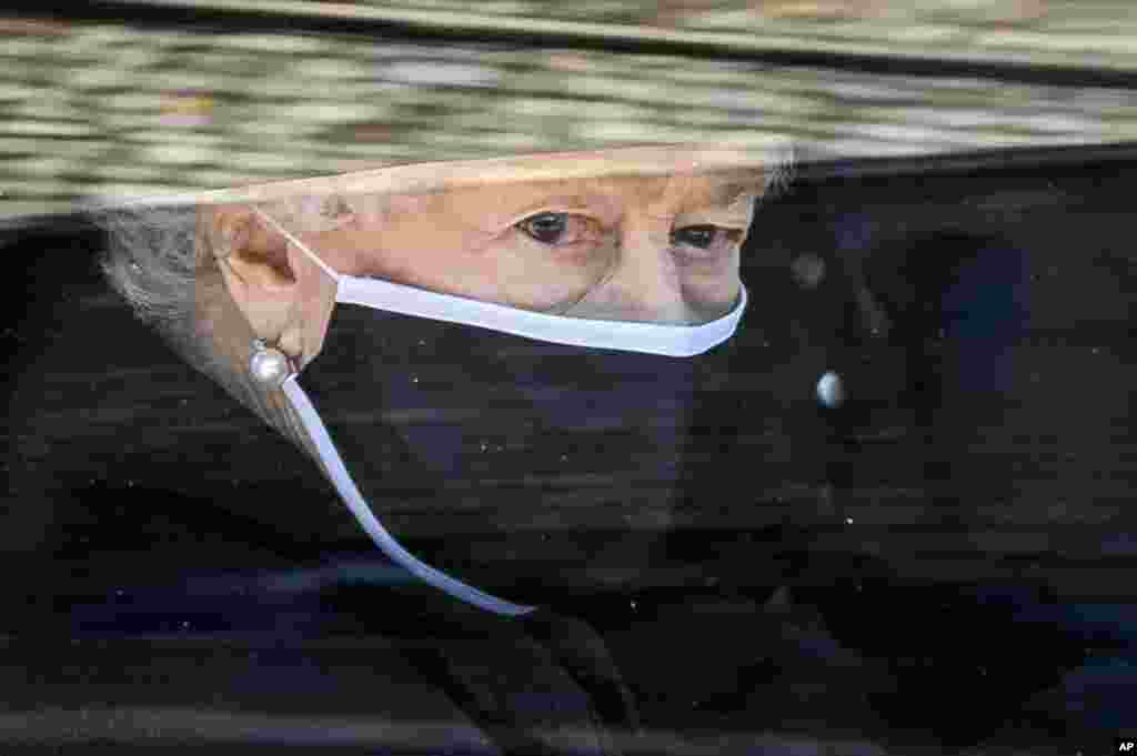 Britain&#39;s Queen Elizabeth II follows the coffin of her late husband Prince Philip, in a car as it makes it&#39;s way past the Round Tower during his funeral inside Windsor Castle in Windsor, England, April 17, 2021.
