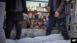 Dječak gleda tijela Palestinaca ubijenih u izraelskom bombardovanju pojasa Gaze dok ih donose na sahranu u bolnicu Al-Aqsa u Deir al-Balahu, 15. januara 2025.
