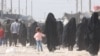 Sejumlah perempuan tampak berjalan di area Kamp Al-Hol, di Suriah, pada 20 Oktober 2021. Kamp tersebut sebagian besar dihuni oleh perempuan dan anak-anak yang ditahan karena memiliki keterkaitan dengan ISIS. (Foto: VOA/Ali Zeyno)