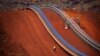 FILE - A worker walks near conveyer belts loaded with iron ore at the Fortescue Solomon iron ore mine located in the Valley of the Kings, around 400 km (248 miles) south of Port Hedland in the Pilbara region of Western Australia.